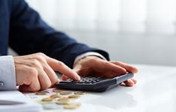 A man in a suit using a calculator